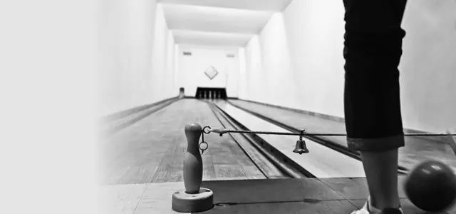 Blick über eine Kegelbahn mit Kugelrücklauf auf die aufgestellten Kegel